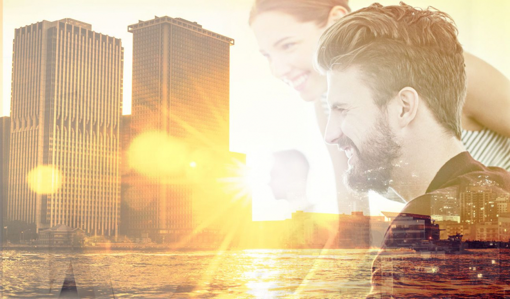 A man and woman collaborating overlaid with a cityscape at sunset