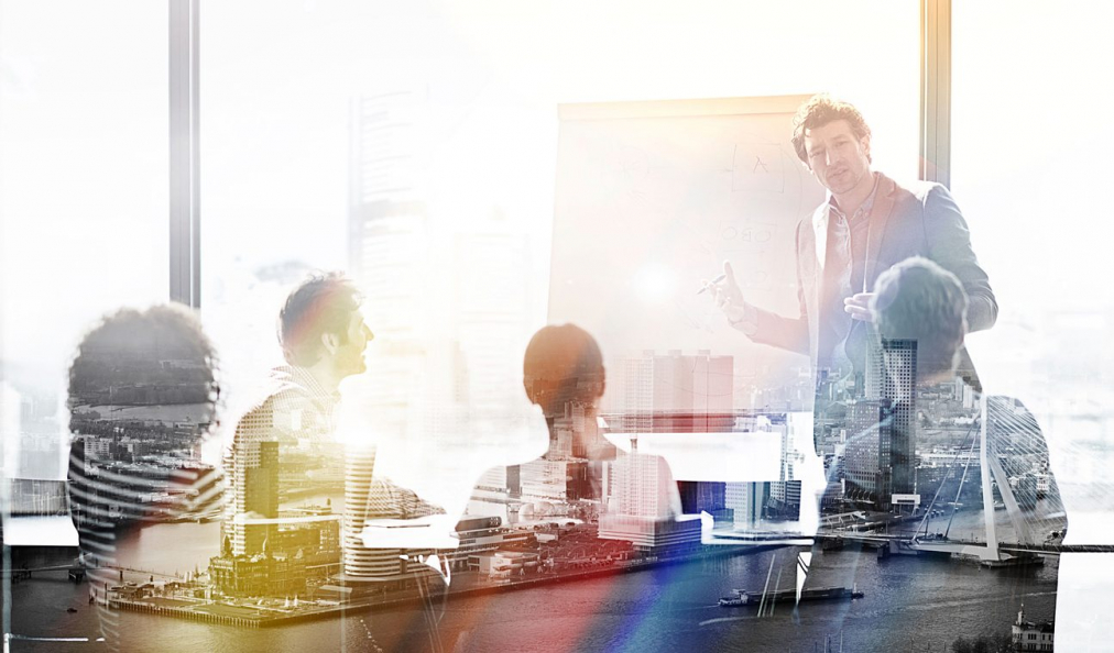 Group of people in a board room discussion overlaid with colourful rays of sunlight