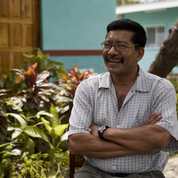 A Liberation Nuts farmer sat smiling in a green garden area