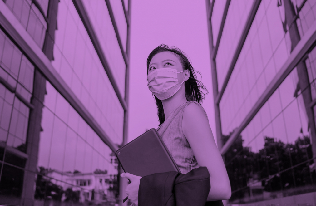 Profile of a woman wearing a mask with office buildings in the background