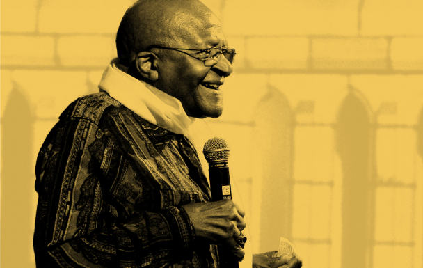 A smiling Archbishop Desmond Tutu with microphone in hand